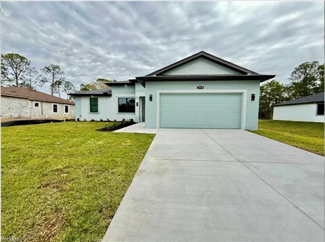 View of front of home featuring a front yard, an attached garage, stucco siding, and driveway