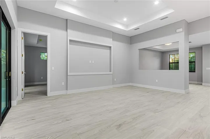 Unfurnished room with a raised ceiling, light wood-type flooring, and recessed lighting