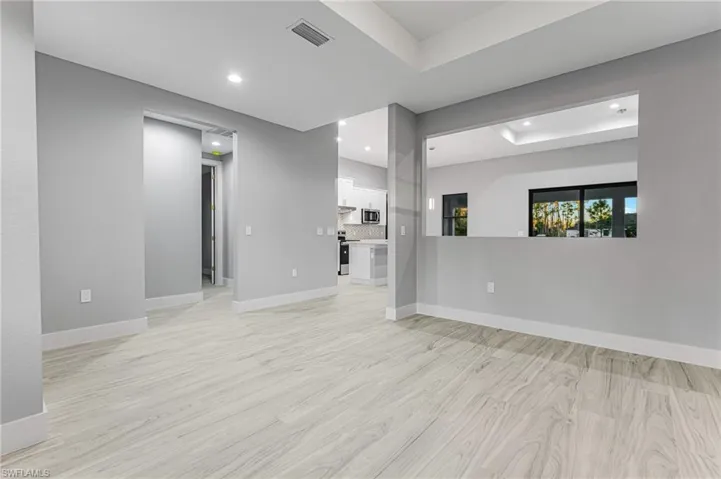 Unfurnished room with light wood finished floors, a tray ceiling, and recessed lighting