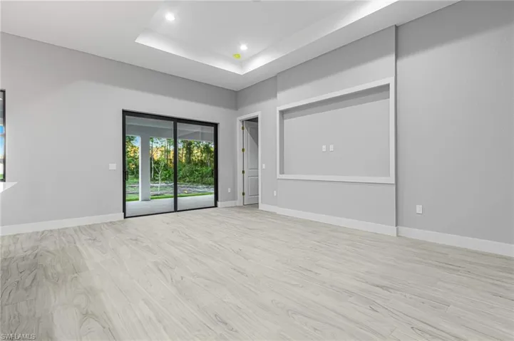 Unfurnished room featuring light wood-style floors, a raised ceiling, and recessed lighting