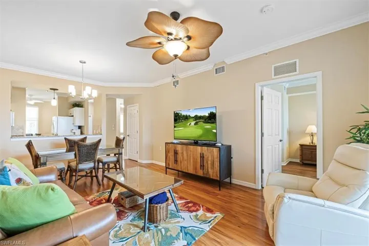 Living area with crown molding, wood finished floors, a ceiling fan, and a chandelier