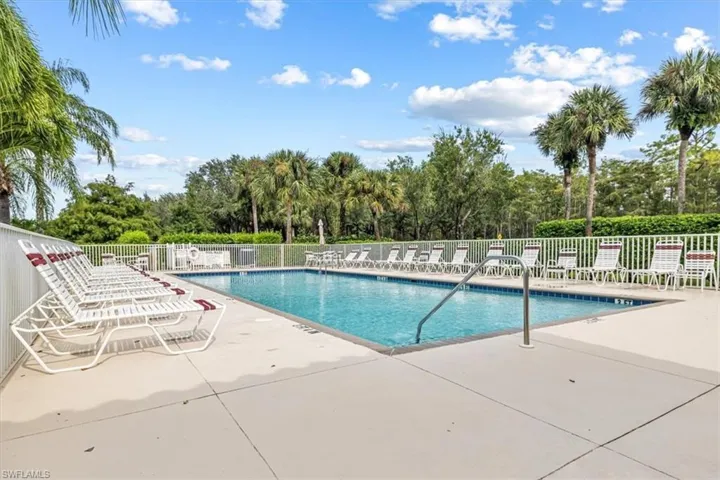 Community pool with a patio area and view of wooded area