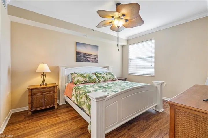 Bedroom featuring crown molding, dark wood-style floors, and ceiling fan