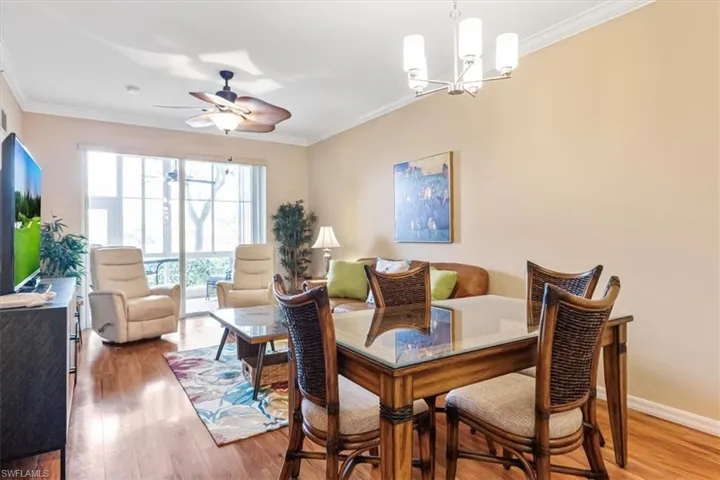 Dining space featuring ornamental molding, light wood-style floors, ceiling fan, and a chandelier