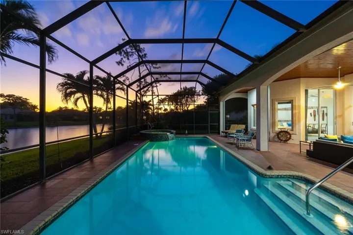 Pool at dusk with a pool with connected hot tub, a lanai, a sunroom, and a patio