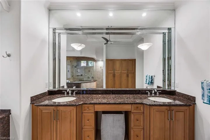 Full bathroom featuring ornamental molding, a tile shower, double vanity, and a ceiling fan
