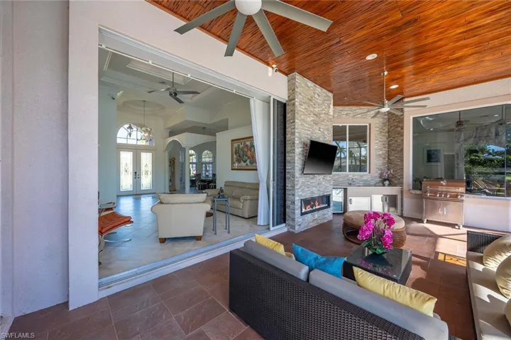 View of patio / terrace with area for grilling, a ceiling fan, an outdoor living space with a fireplace, and french doors