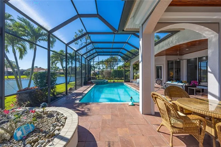 View of pool with a sunroom, a water view, a patio area, a pool with connected hot tub, and glass enclosure