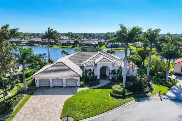 View of front of house featuring a front lawn, a garage, decorative driveway, and a water view