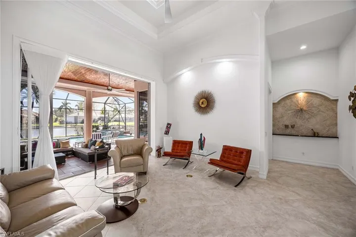 Living area with a sunroom, a towering ceiling, a ceiling fan, and a water view
