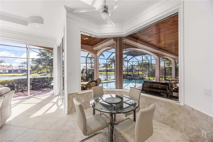 Sunroom / solarium featuring a ceiling fan, a patio, a water view, and outdoor dining space