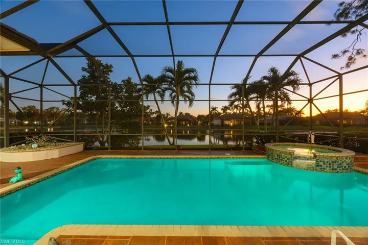 View of pool with a sunroom, glass enclosure, a pool with connected hot tub, and a water view