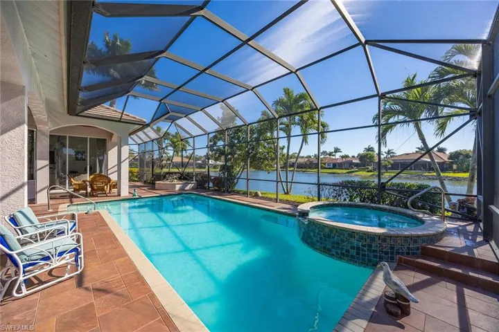 View of pool featuring a patio, a sunroom, a pool with connected hot tub, and glass enclosure