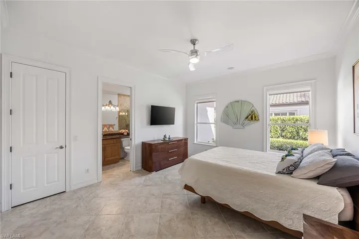 Bedroom with crown molding, a ceiling fan, and ensuite bath
