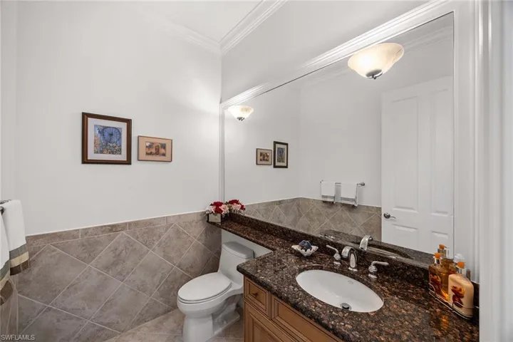 Bathroom featuring vanity, tile walls, crown molding, and wainscoting