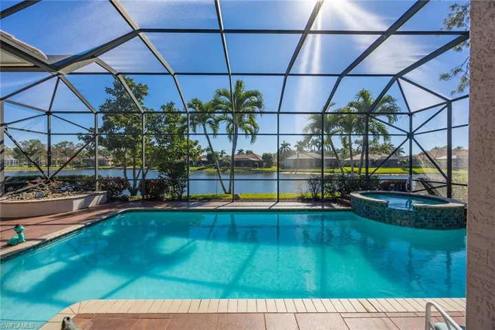 View of swimming pool featuring a sunroom, a pool with connected hot tub, a lanai, a water view, and a residential view