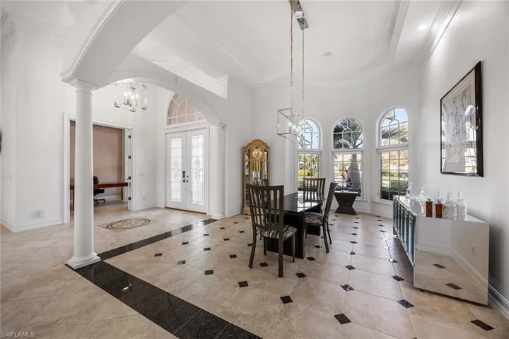 Dining area with french doors, a chandelier, ornate columns, arched walkways, and a high ceiling