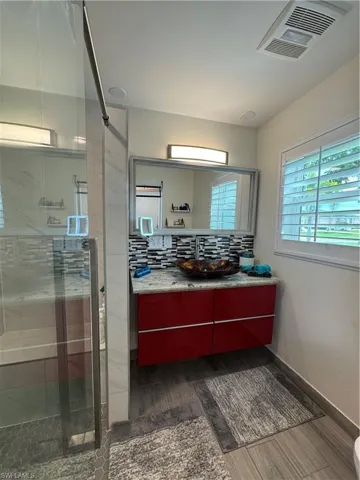 Bathroom with vanity, a shower stall, dark wood-style floors, and tasteful backsplash