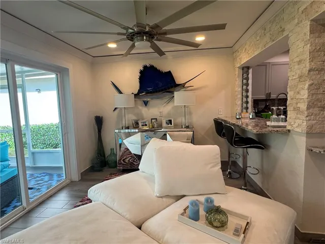 Living room with crown molding, wood finished floors, ceiling fan, and recessed lighting