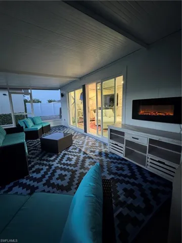 Living room featuring a glass covered fireplace and beam ceiling