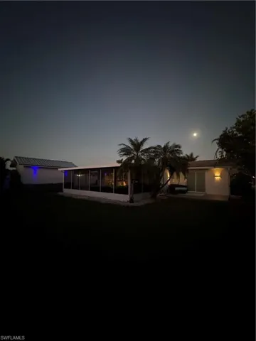 Back of house featuring a lawn and a sunroom