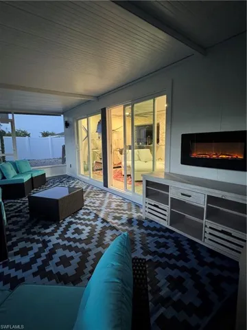 Bedroom featuring access to exterior, a glass covered fireplace, and beamed ceiling