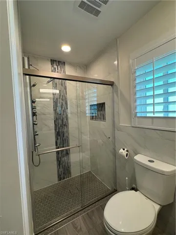 Full bathroom with a stall shower, tile walls, recessed lighting, and wood finished floors