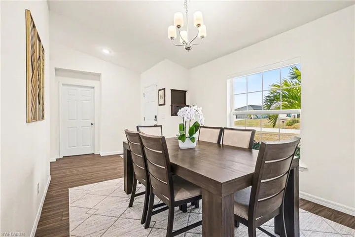 Dining space with lofted ceiling, hanging lights, and dark wood-style flooring