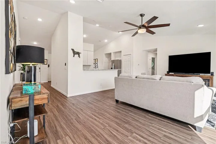 Living room with wood finished floors, ceiling fan, lofted ceiling, and recessed lighting