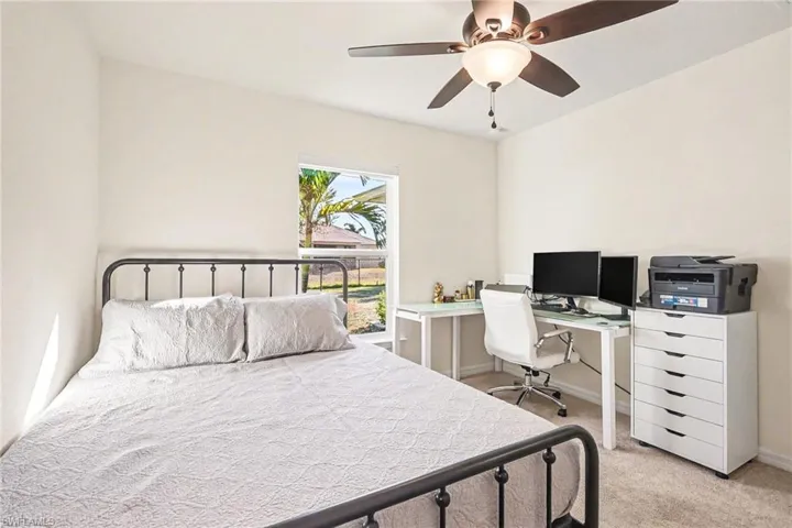 Bedroom with a desk, light carpet, and a ceiling fan