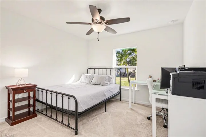 Bedroom with an office area, a ceiling fan, and light colored carpet