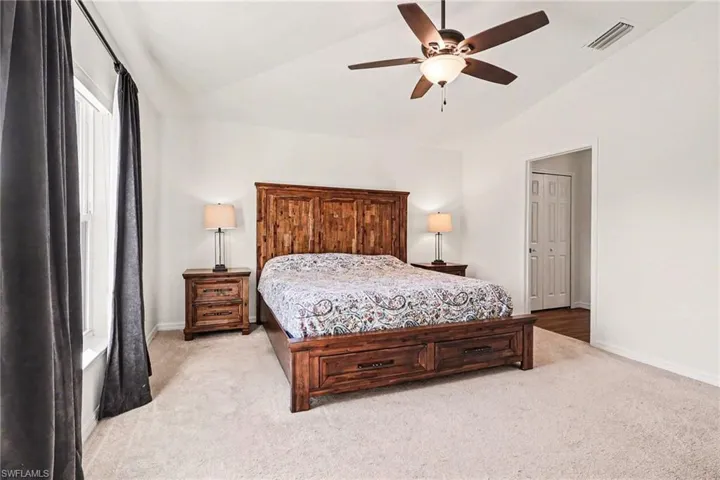 Bedroom featuring vaulted ceiling, light colored carpet, and ceiling fan