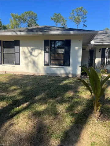 View of side of home featuring stucco siding and a yard