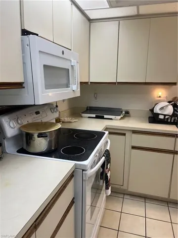 Kitchen featuring white range, light tile patterned flooring, light countertops, and white cabinetry