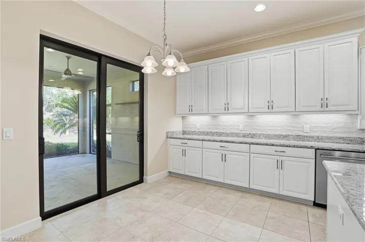 Kitchen featuring white cabinetry, light stone counters, dishwasher, ceiling fan, and ornamental molding