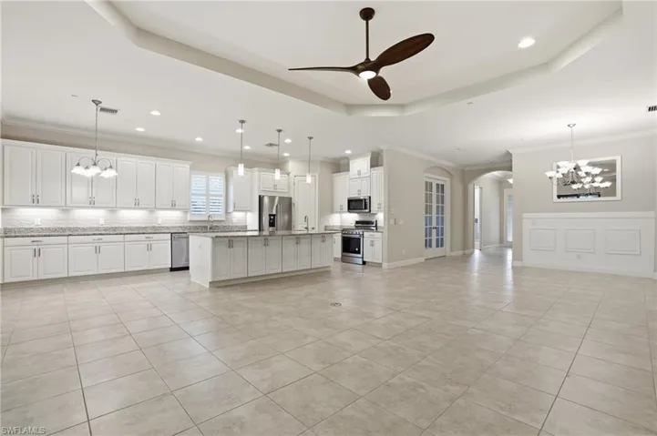 Kitchen featuring hanging lights, arched walkways, a ceiling fan, tasteful backsplash, and white cabinetry