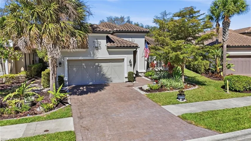 Mediterranean / spanish-style house with decorative driveway, stucco siding, an attached garage, a front lawn, and a tiled roof