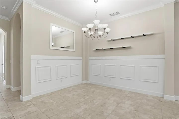 Unfurnished dining area with ornamental molding, arched walkways, a chandelier, and light tile patterned floors