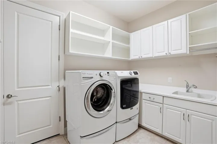 Laundry area featuring washer and clothes dryer, cabinet space, and light tile patterned floors