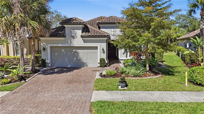 Mediterranean / spanish house featuring decorative driveway, an attached garage, a front yard, and stucco siding
