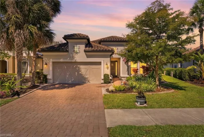 Mediterranean / spanish home featuring a garage, driveway, stucco siding, a yard, and a tile roof