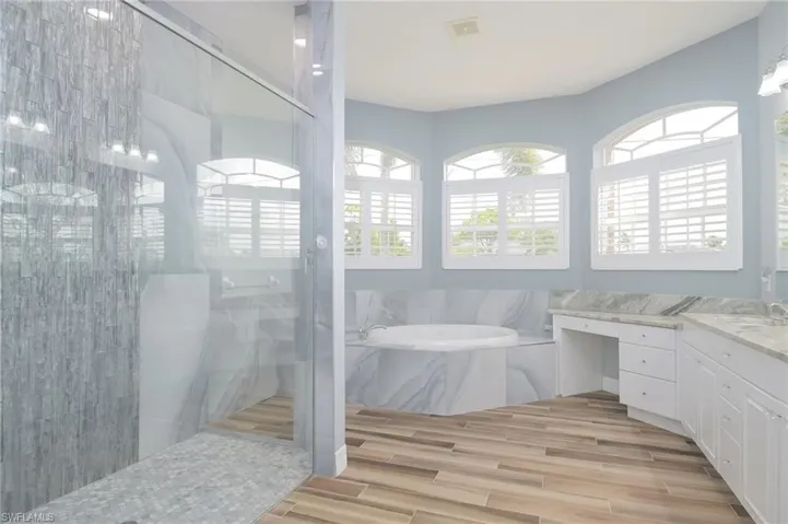 Bathroom featuring separate shower and tub, vanity, and tile walls