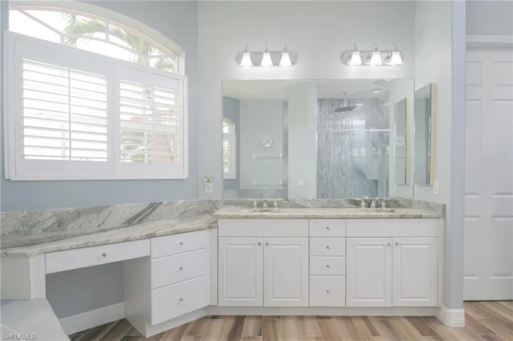 Bathroom with hardwood / wood-style floors, a wealth of natural light, large vanity, and dual sinks