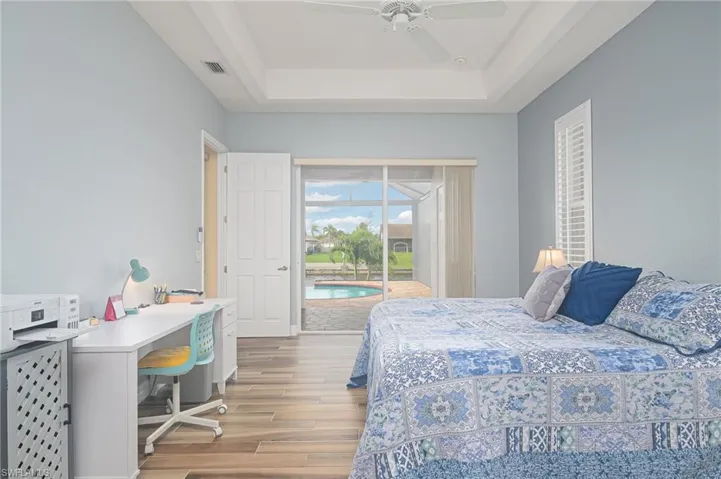 Bedroom with a raised ceiling, ceiling fan, access to exterior, and light hardwood / wood-style flooring