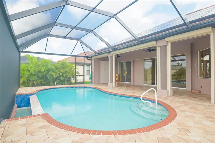 View of pool with ceiling fan, glass enclosure, and a patio