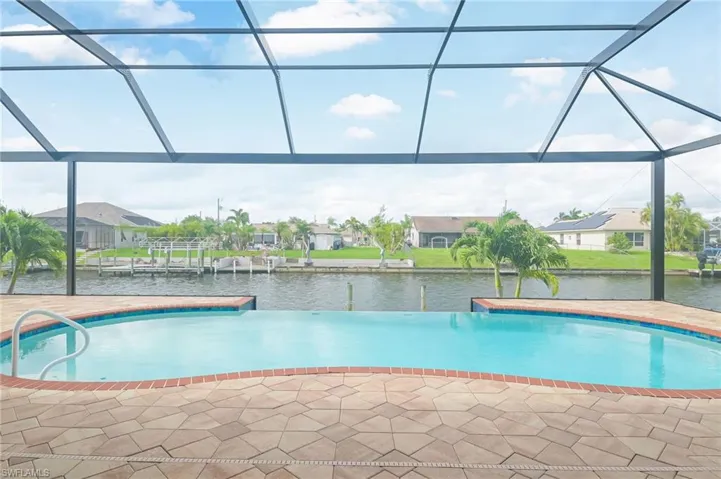 View of swimming pool with glass enclosure and a water view