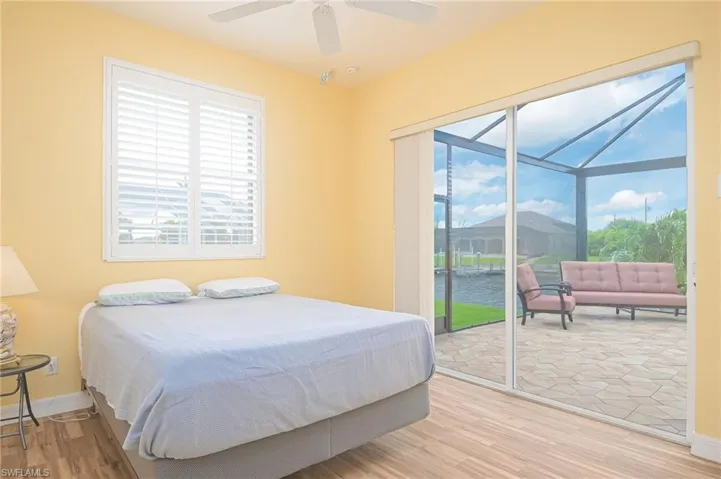 Bedroom featuring access to exterior, light wood-type flooring, a water view, and ceiling fan
