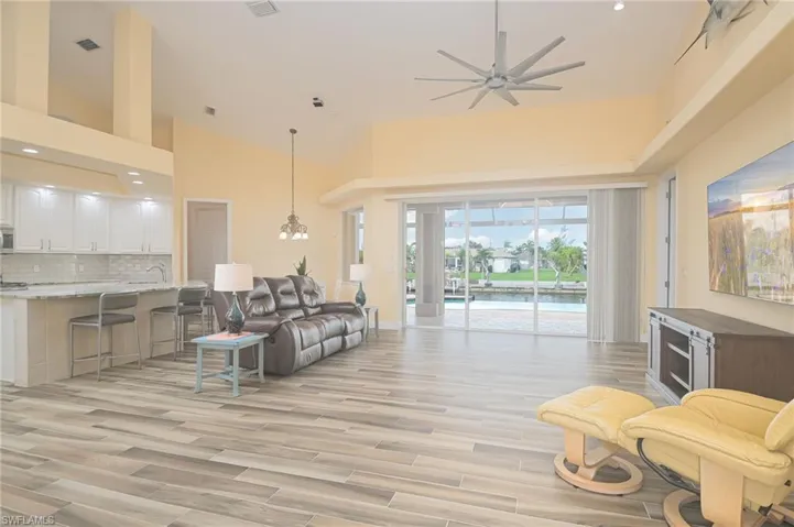 Living room featuring a high ceiling, light hardwood / wood-style floors, and ceiling fan with notable chandelier