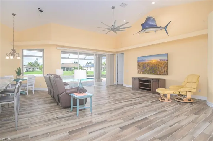 Living room featuring high vaulted ceiling, light wood-type flooring, and ceiling fan with notable chandelier