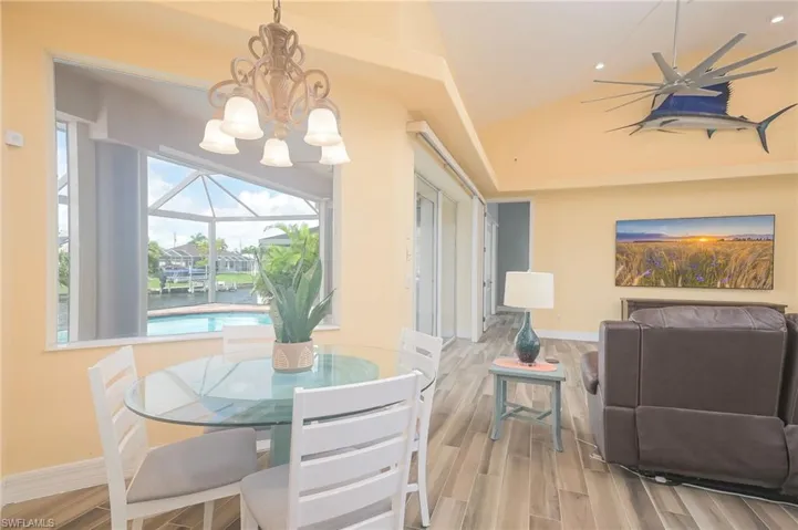 Dining space with vaulted ceiling, an inviting chandelier, and light wood-type flooring